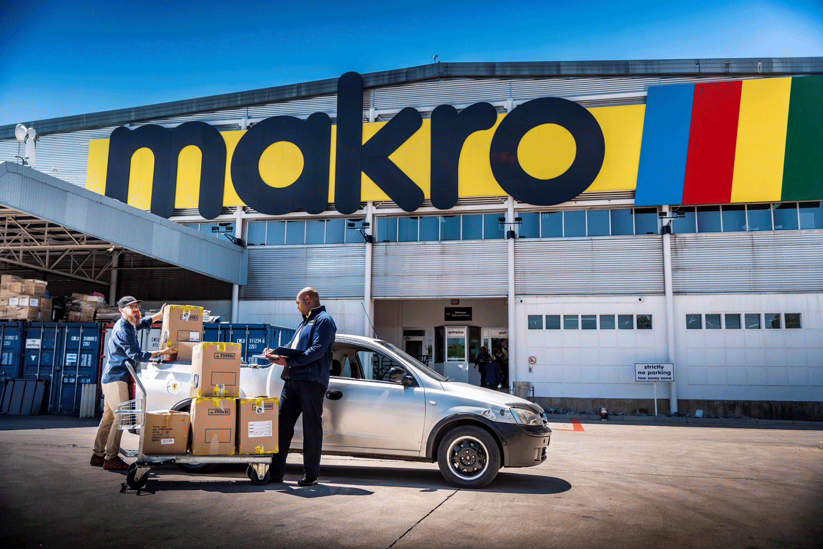 Exterior of a Makro store. An associate loas merchandise into a customer's car.